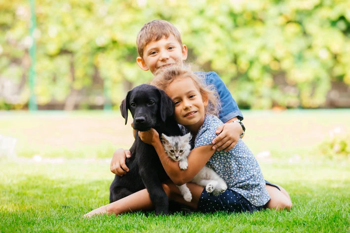 crianças segurando gato e cachorro