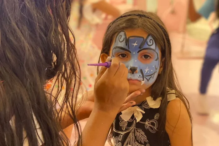 menina fazendo borboleta azul no rosto