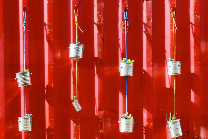 vasos suspensos feitos com latas na parede vermelha